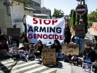 Protesters with signs against arms and genocide.