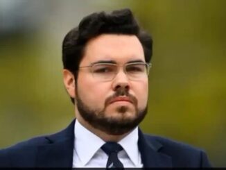 Man with glasses wearing a suit outdoors.