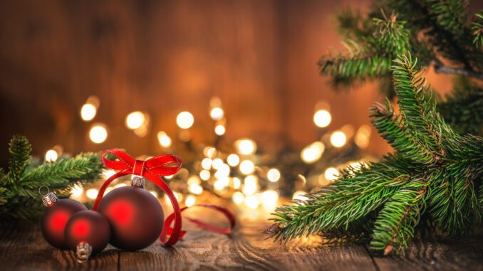 Red baubles and pine branches, festive lights.