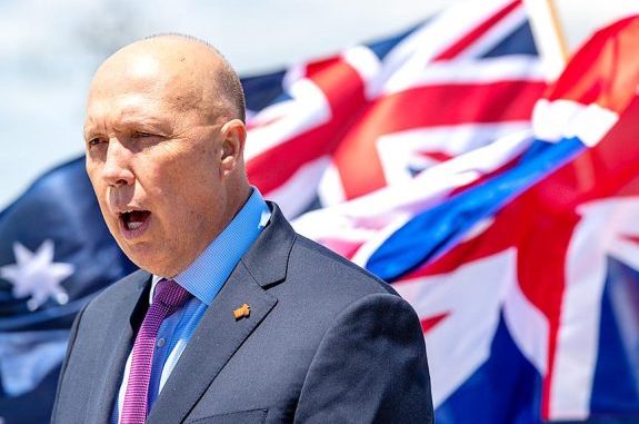 Person speaking with Australian flag behind them. Person speaking with Australian flag behind them.