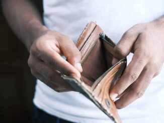Person holding empty brown leather wallet.
