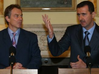 Two men at podiums, one making a gesture
