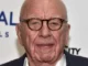 Elderly man with glasses, smiling at event.
