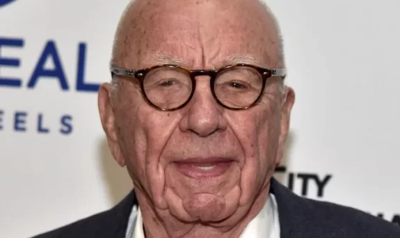 Elderly man with glasses, smiling at event.