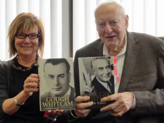 Two people holding books about Gough Whitlam.