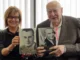 Two people holding books about Gough Whitlam.