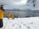People in yellow jackets on snowy landscape.