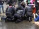 Police officers detaining a person during protest.