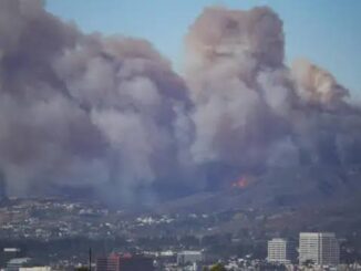 Large smoke clouds over city skyline.
