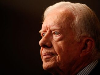 Elderly man gazing thoughtfully into distance.
