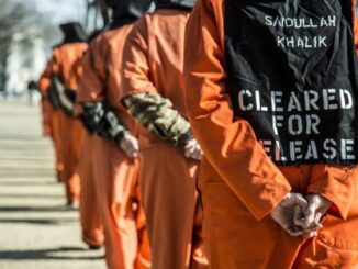 People in orange jumpsuits standing in line.