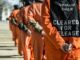 People in orange jumpsuits standing in line.