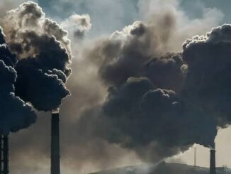 Factory chimneys emit dark smoke clouds.