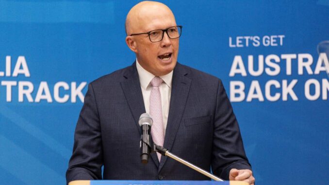 Man speaking at podium with blue background.