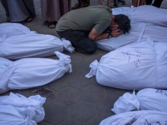 Person mourning among several covered bodies.