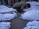 Person mourning among several covered bodies.