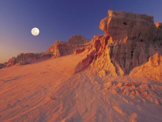 Desert landscape with moon and rock formations.