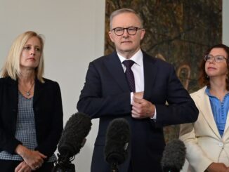 Three people speaking at a press conference.