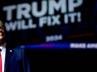 Man in suit with "Trump Will Fix It" sign.