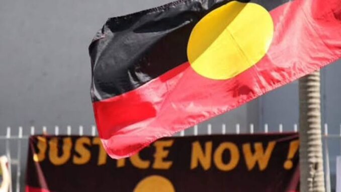 Aboriginal flag with "Justice Now" banner.