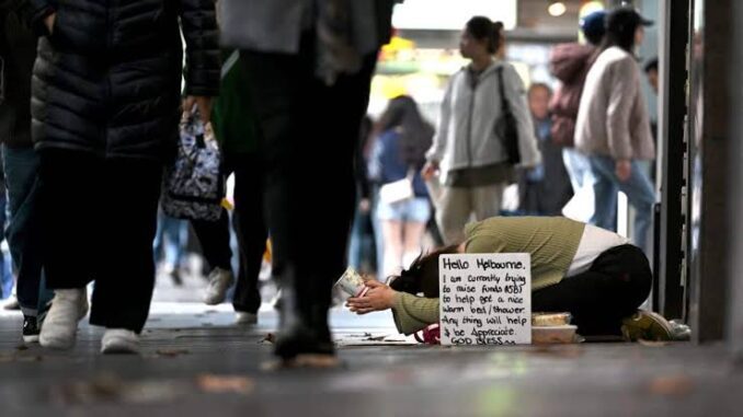 Person kneeling with sign on busy street. Person kneeling with sign on busy street.