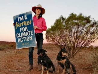 Farmer with climate action sign and dogs.