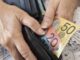 Hands holding wallet with Australian banknotes.