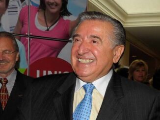 Older man in pinstripe suit laughing warmly