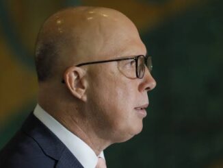Man in suit and glasses, side profile.
