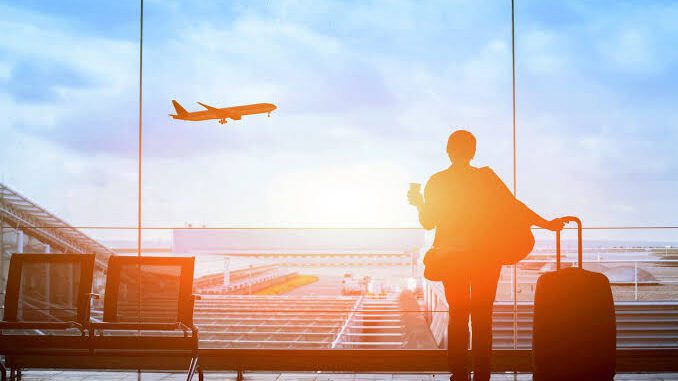 Traveler watching airplane take off at airport.