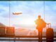 Traveler watching airplane take off at airport.