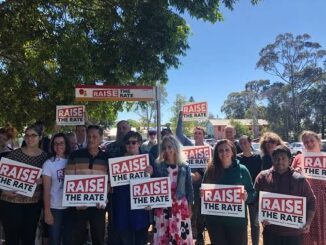 Group holding "Raise the Rate" signs outdoors.