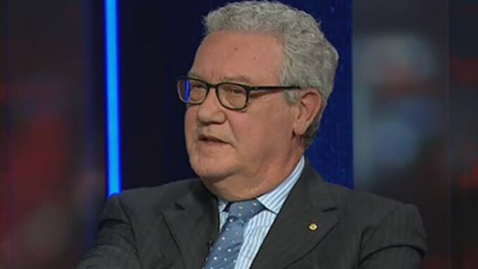 Man in suit speaking on television set.