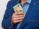 Man putting Australian dollars in jacket pocket.