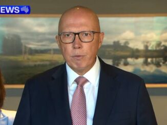 Man in suit speaking at news interview.