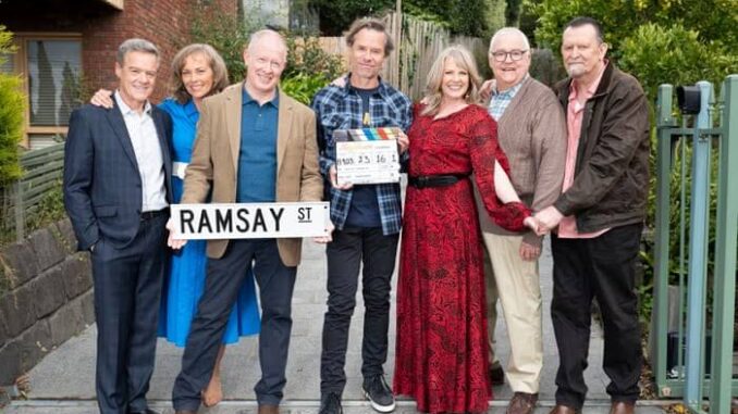 Group of people standing with Ramsay Street sign.