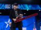 Person holding chainsaw on stage, smiling.
