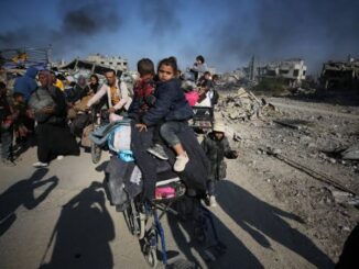 People amidst rubble and destruction, carrying belongings.