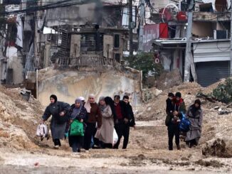 People walking through a war-torn street.
