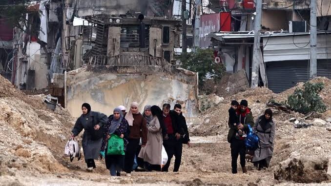 People walking through a war-torn street. People walking through a war-torn street.