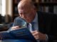 Man reading book with magnifying glass.