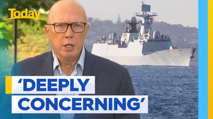 Man speaking with warship in background. Man speaking with warship in background.