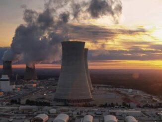 Nuclear power plant at sunset, emitting steam.