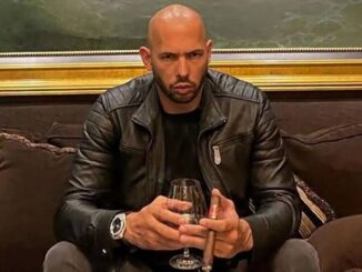 Man holding glass and cigar on couch.
