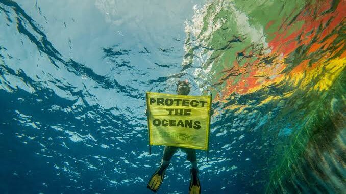 Diver holding "Protect the Oceans" sign underwater. Diver holding "Protect the Oceans" sign underwater.