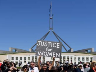 Protesters holding "Justice for Women" sign outside building.