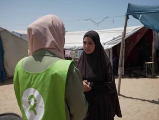 Two women conversing outside in a camp.