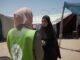Two women conversing outside in a camp.