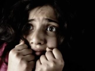 Frightened girl with hands near face.