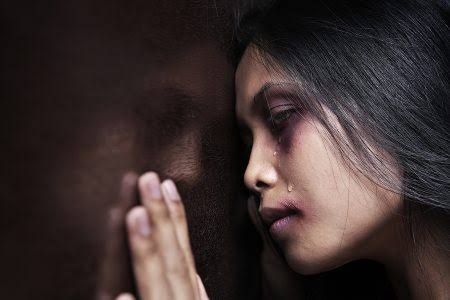 Woman with tear-streaked face against wall.